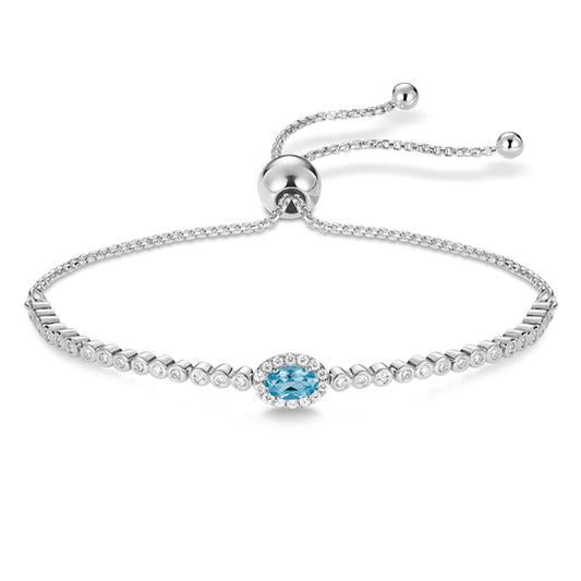 Bracelet fin en chaîne dorée avec pierre de topaze bleue Swiss, bijou délicat et raffiné, photographié sur fond neutre.