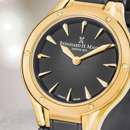 Montre femme dorée Le Classique avec cadran élégant et bracelet métal poli, présentée sur fond neutre.